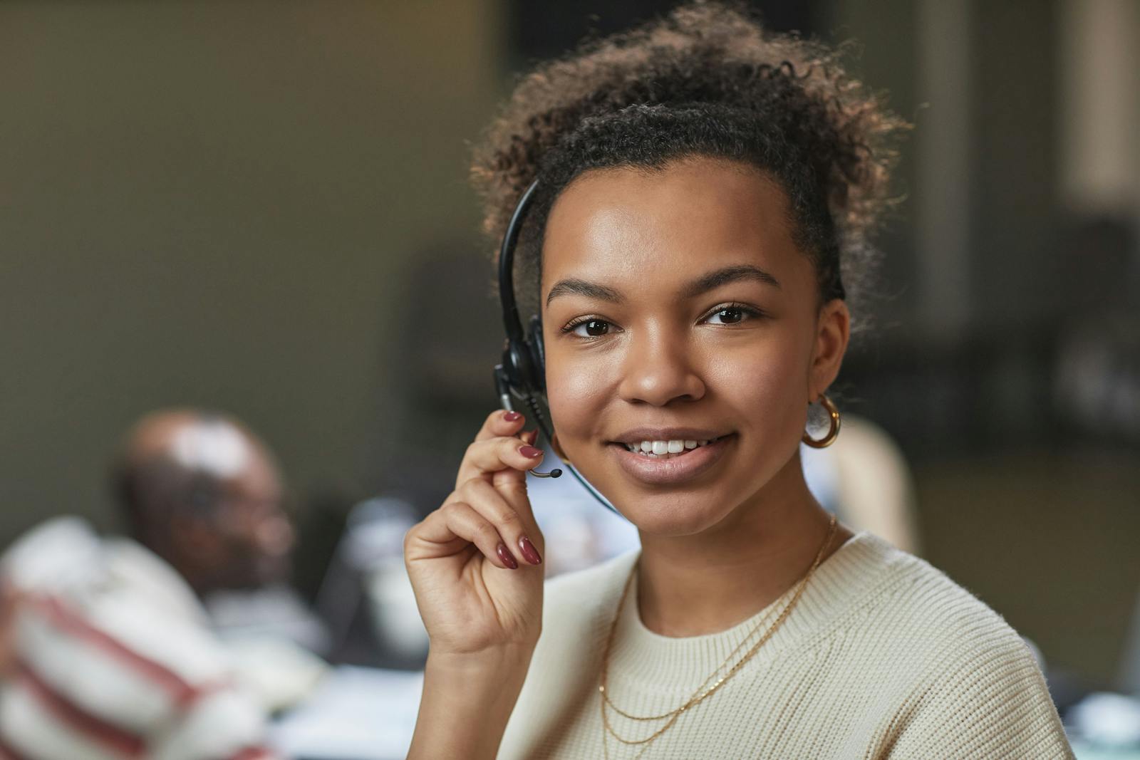 Femme sympathique dans un centre d'appel, portant un casque et souriante.