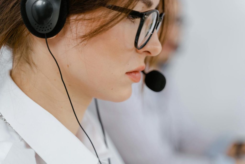 Une jeune femme avec des lunettes et un casque se concentre intensément sur son travail dans un bureau.