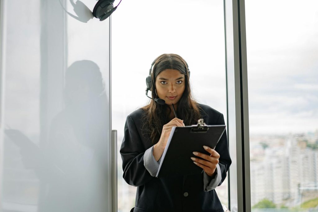 Femme confiante avec un casque travaillant avec un presse-papiers dans un bureau moderne.