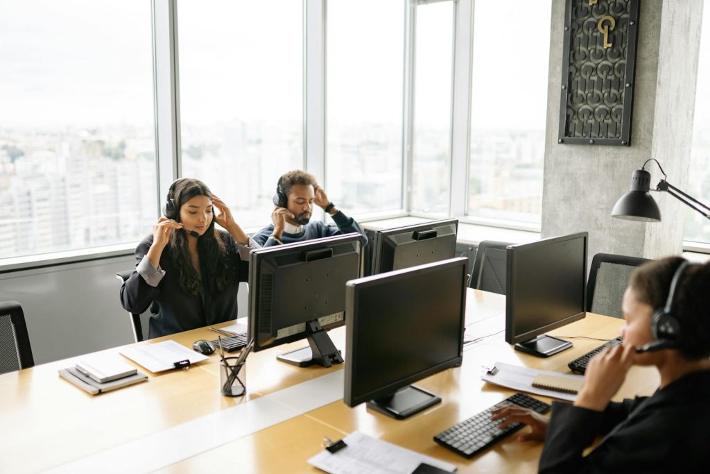 Des agents de centre d'appel concentrés travaillant sur des ordinateurs avec des écouteurs dans un bureau lumineux.